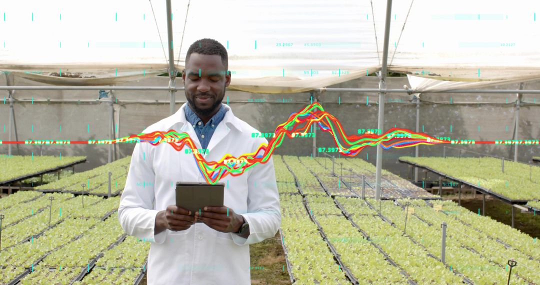Researcher Analyzing Data in Modern Greenhouse with Seedlings