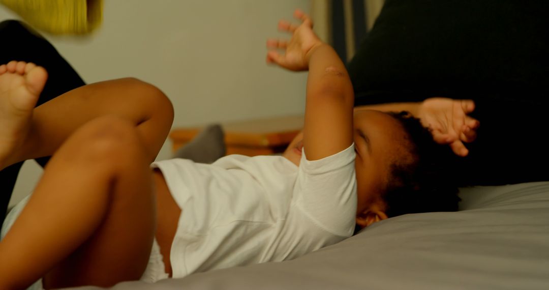 Laughing African American Toddler Playing on Bed with Parent - Free Images, Stock Photos and Pictures on Pikwizard.com