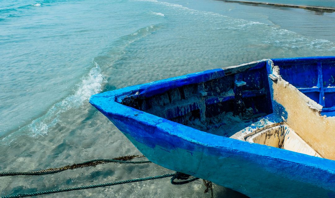 Weathered Blue Boat Ashore on Calm Beach Waters - Free Images, Stock Photos and Pictures on Pikwizard.com