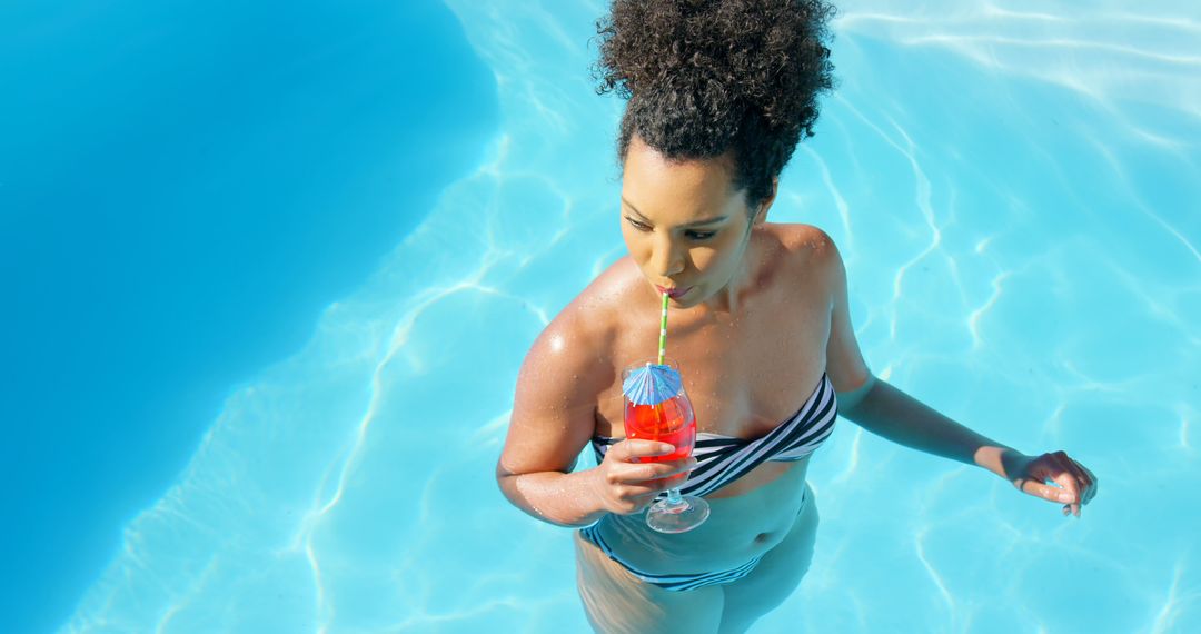 Woman Drinking Cocktail in Pool with Striped Bikini - Free Images, Stock Photos and Pictures on Pikwizard.com