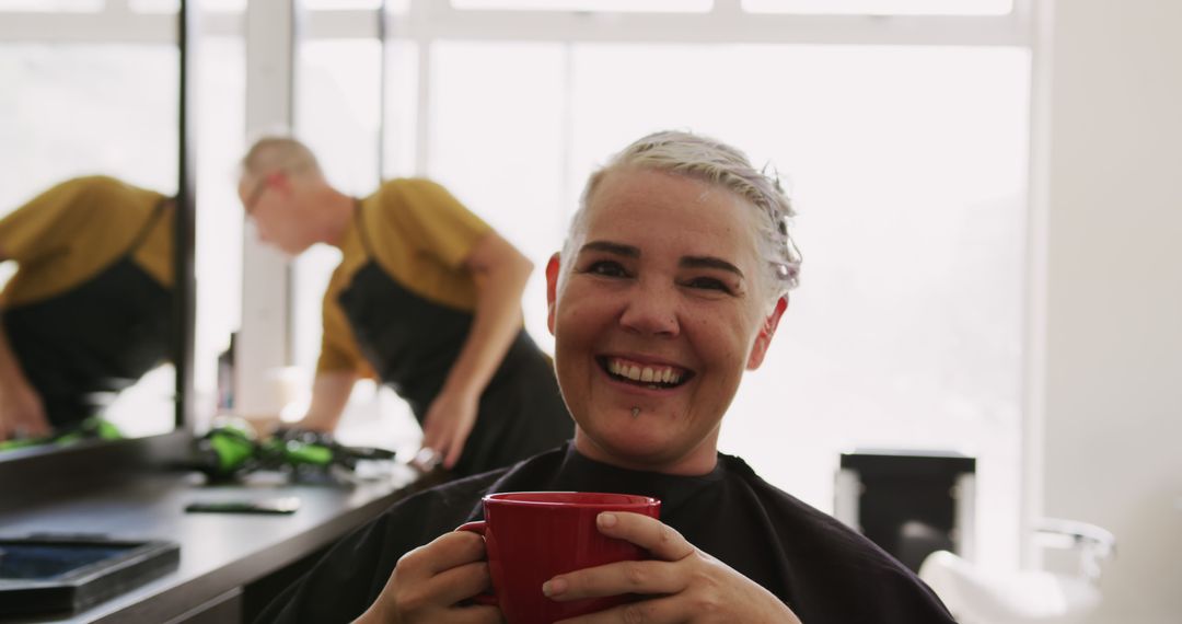 Woman Enjoying Coffee at Hair Salon, Hairdresser in Background - Free Images, Stock Photos and Pictures on Pikwizard.com