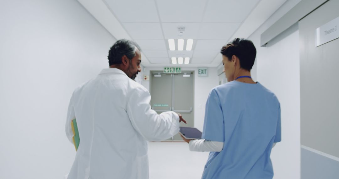 Doctor and Nurse Discussing Patient Records in Hospital Corridor - Free Images, Stock Photos and Pictures on Pikwizard.com