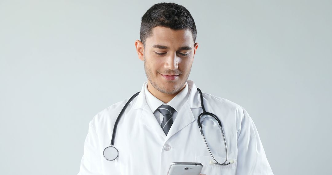 Smiling Biracial Male Doctor Using Smartphone in Office - Free Images, Stock Photos and Pictures on Pikwizard.com