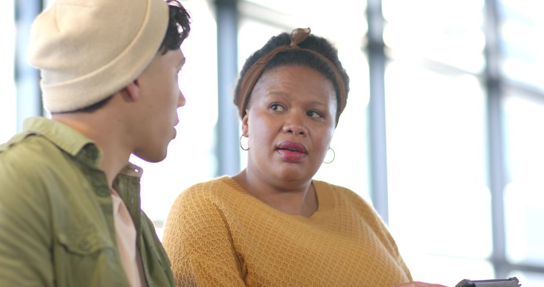 Diverse colleagues discussing on tablet in bright lobby with casual modern workplace vibe