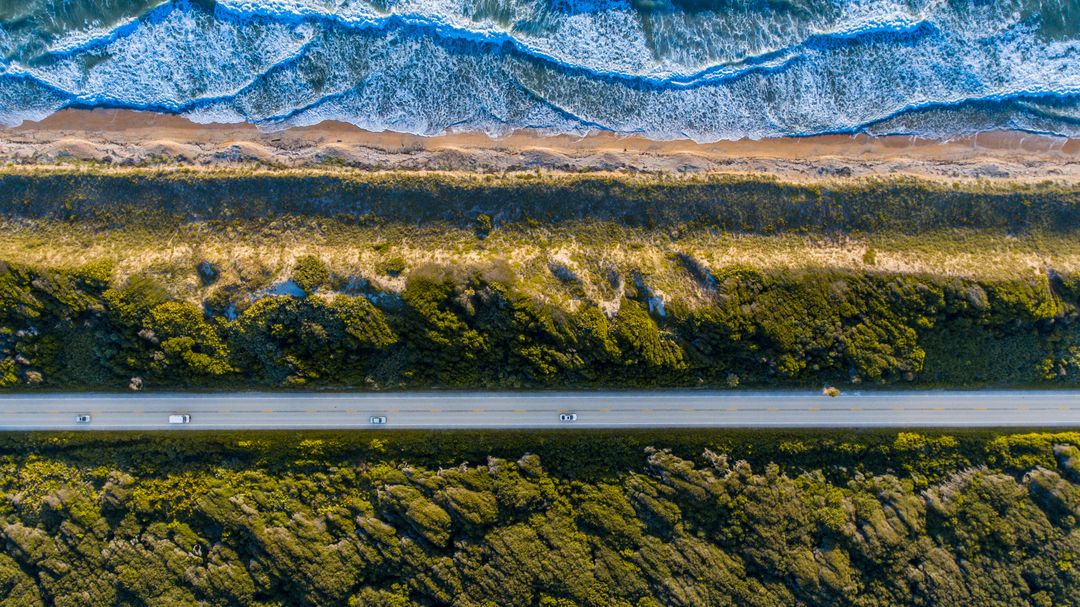Aerial View of Coastal Highway with Lush Vegetation and Ocean Waves - Free Images, Stock Photos and Pictures on Pikwizard.com