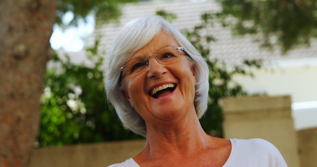 Joyful Senior Woman Smiling Outdoors in Sunny Garden - Free Images, Stock Photos and Pictures on Pikwizard.com