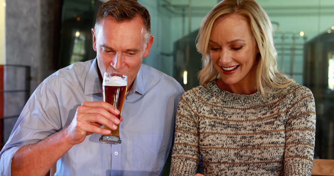 Smiling Middle-Aged Couple Enjoying Beer Indoors with Copy Space