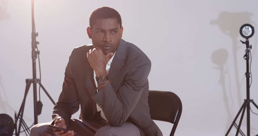 Confident Businessman Reflecting Amid Studio Lights