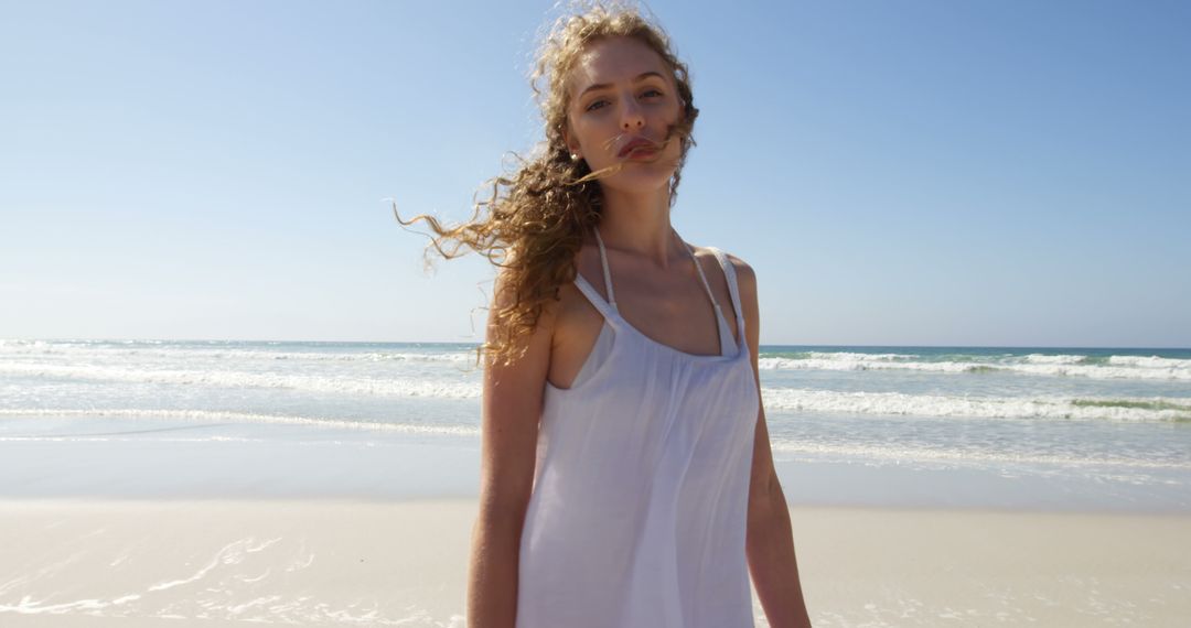 Young Woman Walking on Sunny Beach with Waves in Background - Free Images, Stock Photos and Pictures on Pikwizard.com