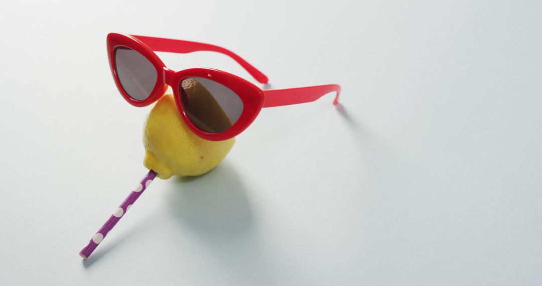 Lemon with Red Sunglasses and Straw on Minimalistic Background