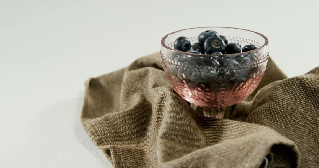 Fresh Blueberries in Vintage Pink Glass Bowl on Brown Fabric - Free Images, Stock Photos and Pictures on Pikwizard.com