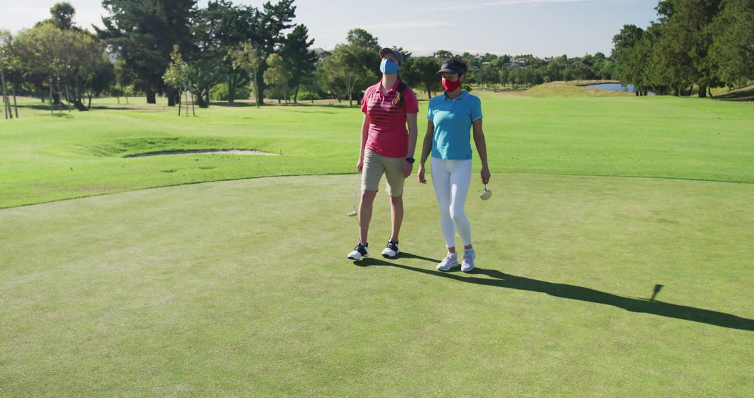 Women Golfers Wearing Face Masks Standing on Golf Course Green - Free Images, Stock Photos and Pictures on Pikwizard.com