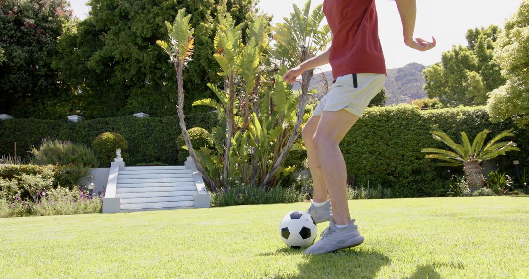 Young Man Practicing Football Tricks in Sunny Garden