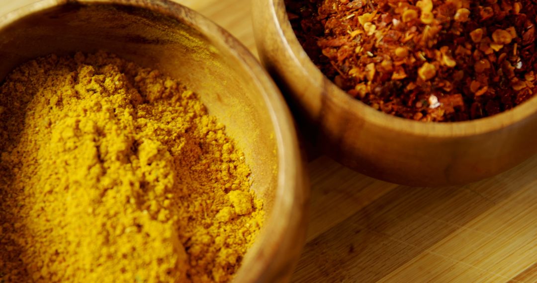 Turmeric and red pepper flakes in wooden bowls exemplify the role of spices in cooking. - Free Images, Stock Photos and Pictures on Pikwizard.com