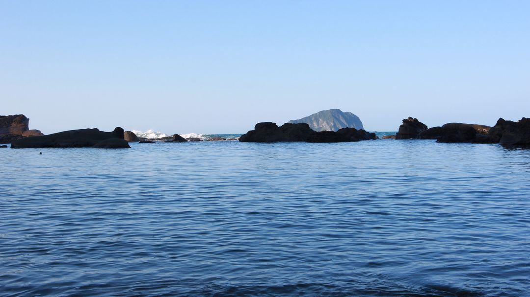 Calm Seascape with Distant Rock Formations and Blue Sky - Free Images, Stock Photos and Pictures on Pikwizard.com