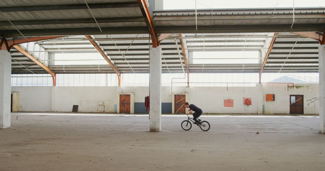 BMX Rider Practicing Stunts in Empty Warehouse - Free Images, Stock Photos and Pictures on Pikwizard.com