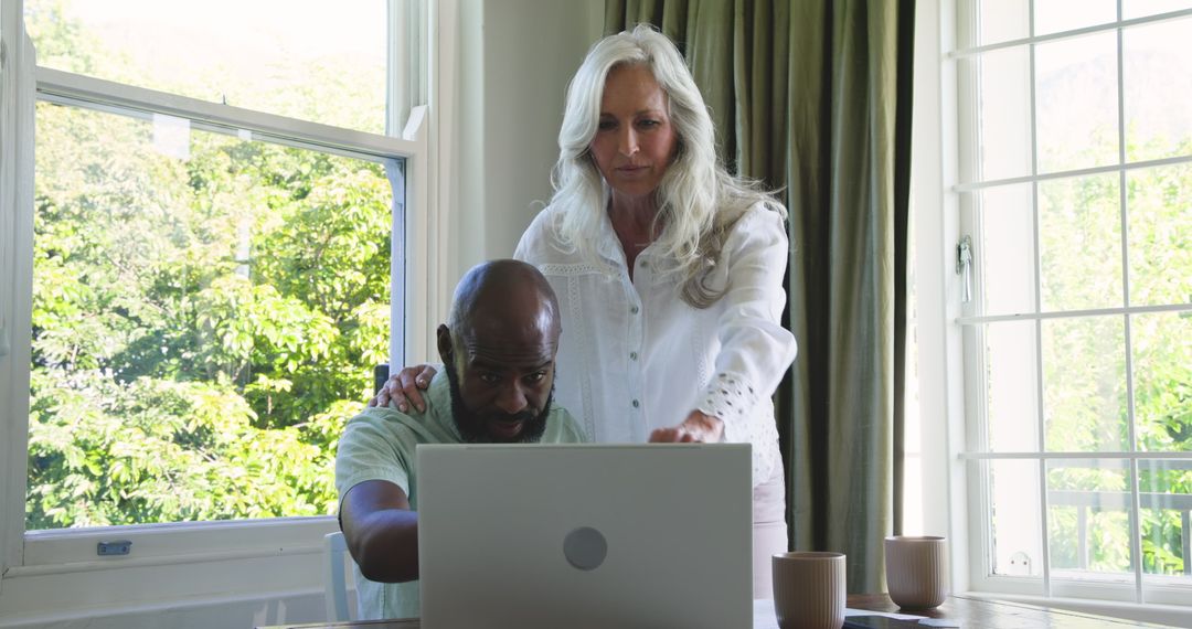 Couple Collaborating on Laptop at Home Near Window