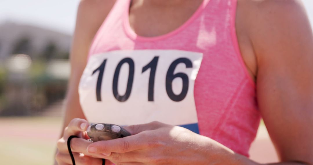 Female Athlete With Race Bib Number 1016 Holding Stopwatch on Track Field - Free Images, Stock Photos and Pictures on Pikwizard.com