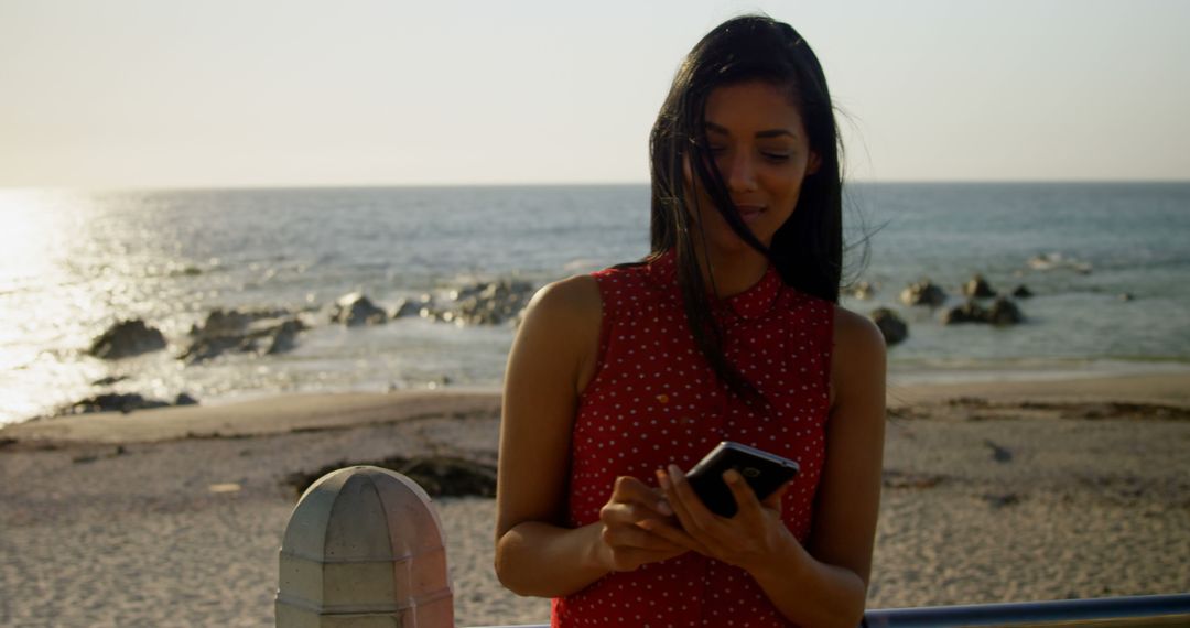 Young woman texting by scenic beach during sunset - Free Images, Stock Photos and Pictures on Pikwizard.com