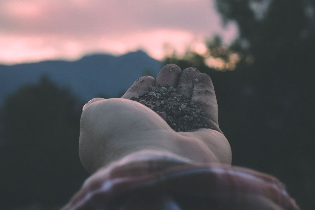 Hand Holding Sand at Sunset with Mountain Background - Free Images, Stock Photos and Pictures on Pikwizard.com