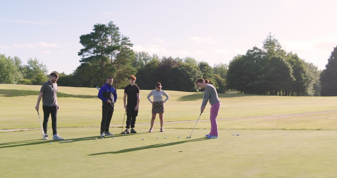 Golfers Practicing Putting on Sunny Day in Green Field