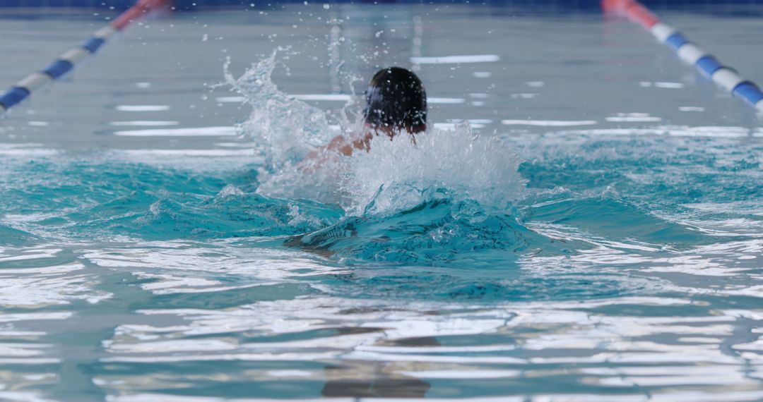 Swimmer Splashing Water in Indoor Pool During Lap Swimming - Free Images, Stock Photos and Pictures on Pikwizard.com