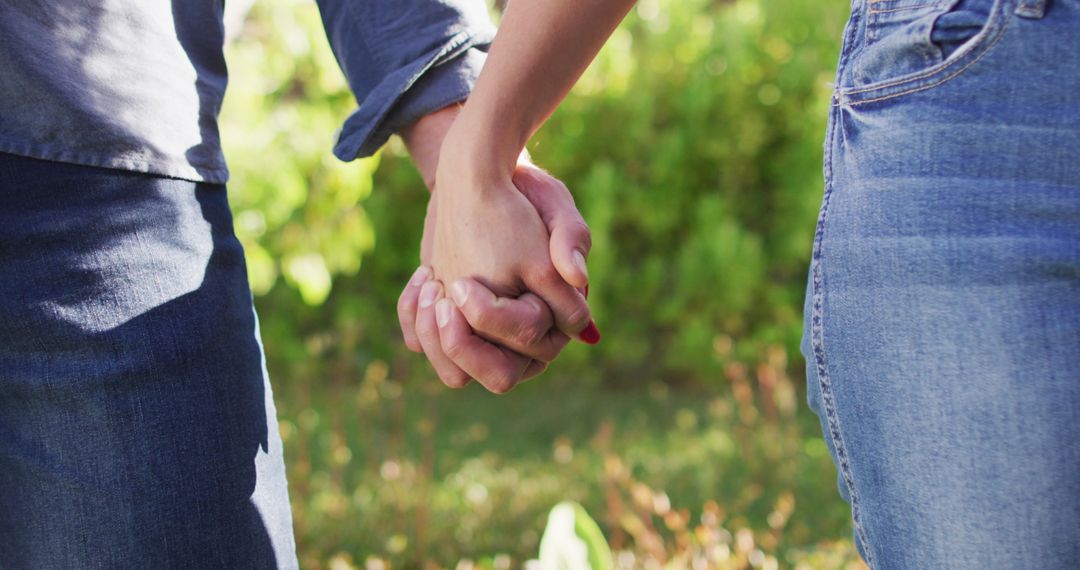 Close-Up of Couple Holding Hands in Sunlit Garden