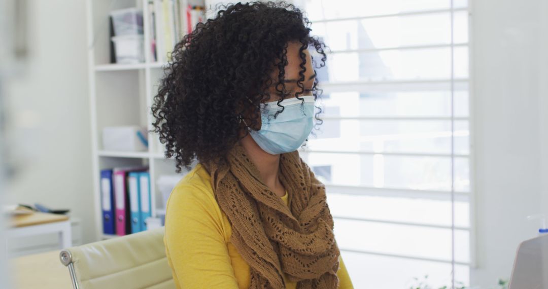 Young Woman with Curly Hair Wearing Protective Face Mask in Office - Free Images, Stock Photos and Pictures on Pikwizard.com