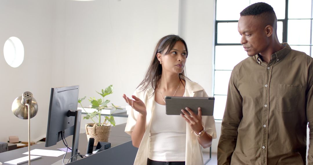 Colleagues Discussing Projects Using Tablet in Modern Office
