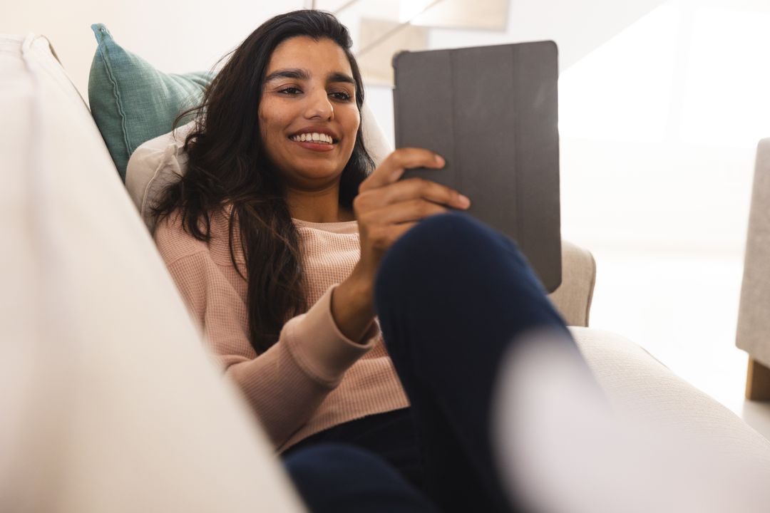 Smiling Woman Using Tablet While Relaxing on Sofa at Home