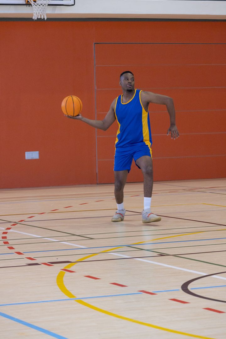 Athlete Strategizing with Basketball Indoors in Action-Packed Gym