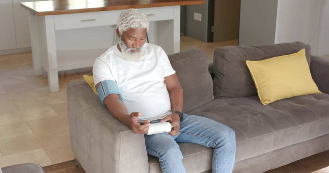 Senior Man Monitoring Blood Pressure at Home Using Digital Device