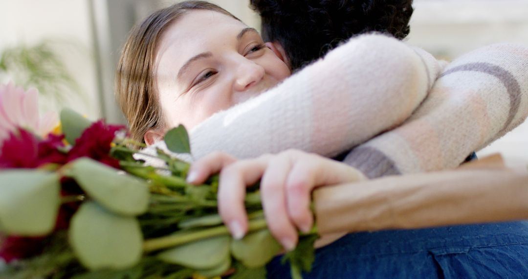 Happy Woman Hugging Friend While Holding Bouquet of Flowers - Free Images, Stock Photos and Pictures on Pikwizard.com