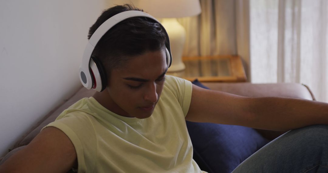 Teen Sitting on Couch Listening to Music with Headphones - Free Images, Stock Photos and Pictures on Pikwizard.com