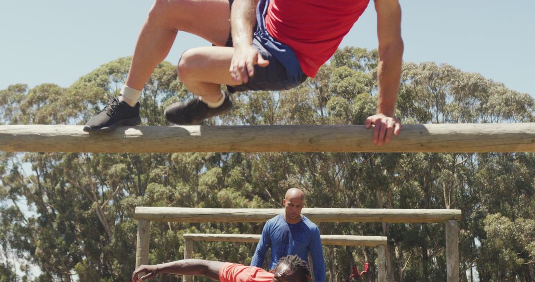 Group Overcoming Hurdle in Outdoor Obstacle Course Training
