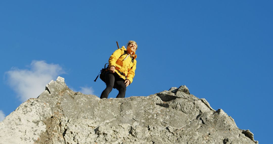 Woman Climbing Rocky Mountain Peak Against Blue Sky - Free Images, Stock Photos and Pictures on Pikwizard.com