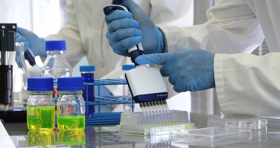 Scientists Wearing Gloves Working in Laboratory with Pipette and Chemical Solutions - Free Images, Stock Photos and Pictures on Pikwizard.com