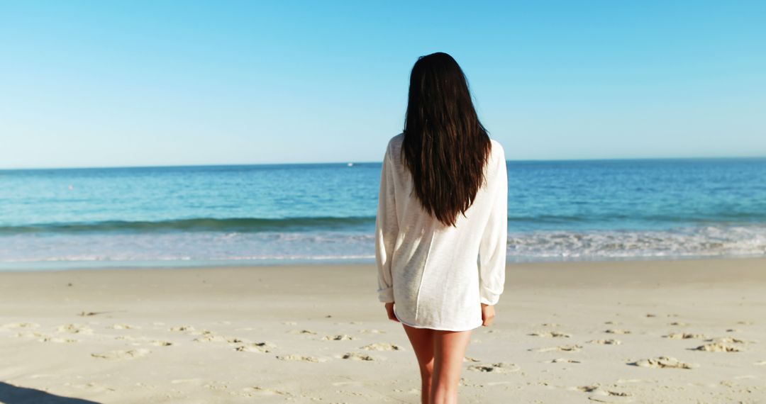 Woman in white shirt enjoying peaceful beach view - Free Images, Stock Photos and Pictures on Pikwizard.com