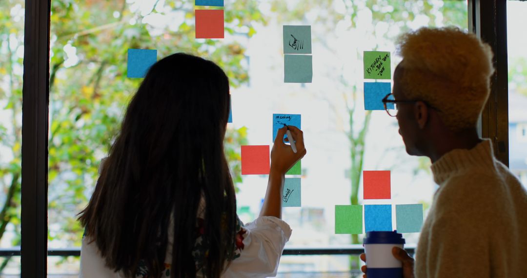 Team Members Collaborating with Sticky Notes on Glass Wall - Free Images, Stock Photos and Pictures on Pikwizard.com