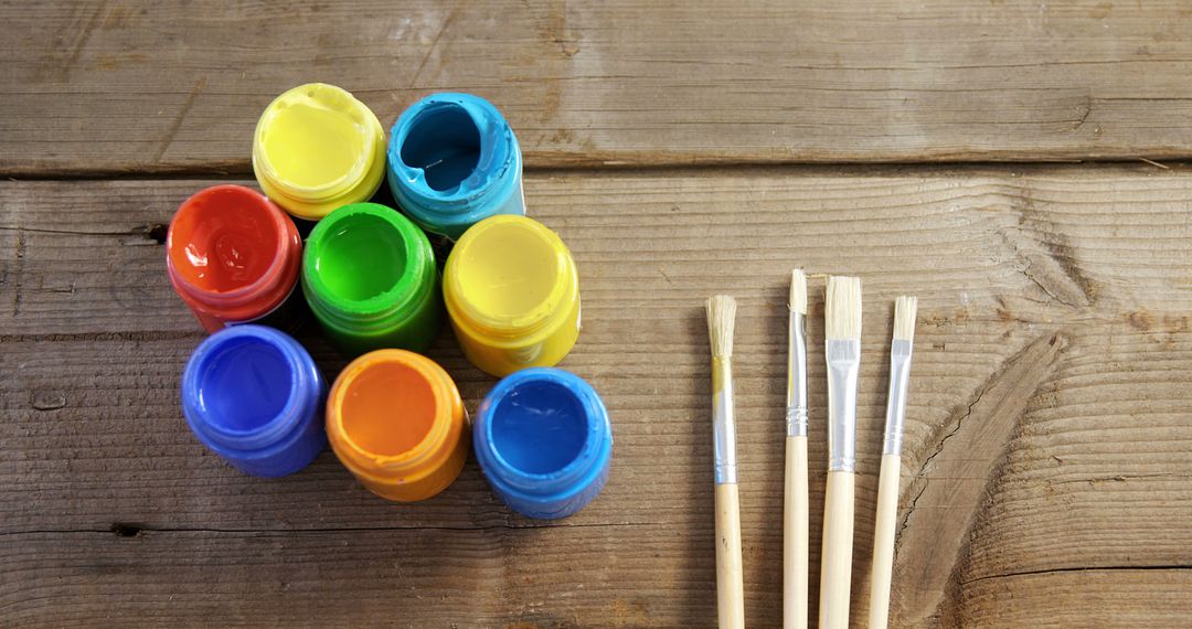 Multicolored Paint Pots and Brushes on Wooden Table - Free Images, Stock Photos and Pictures on Pikwizard.com