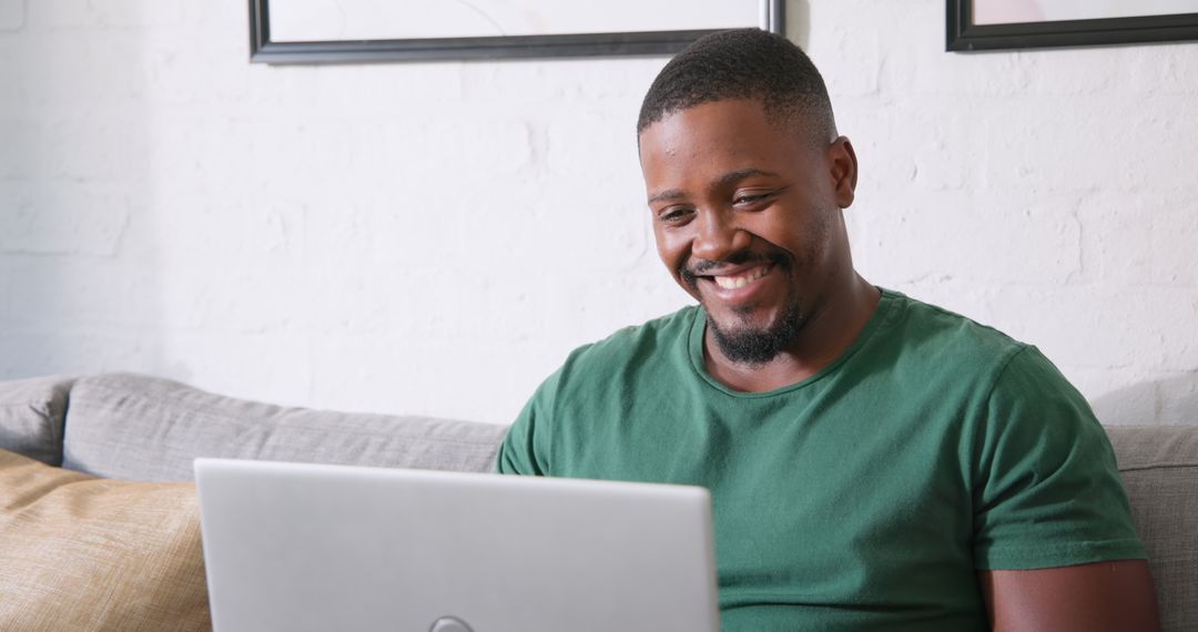 Man Smiling While Using Laptop in Casual Home Office Environment