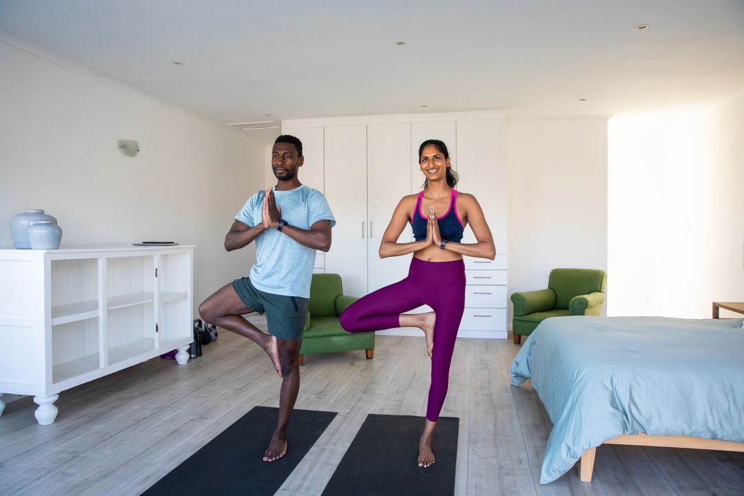 Couple Practicing Yoga Tree Pose Together in Bright Bedroom