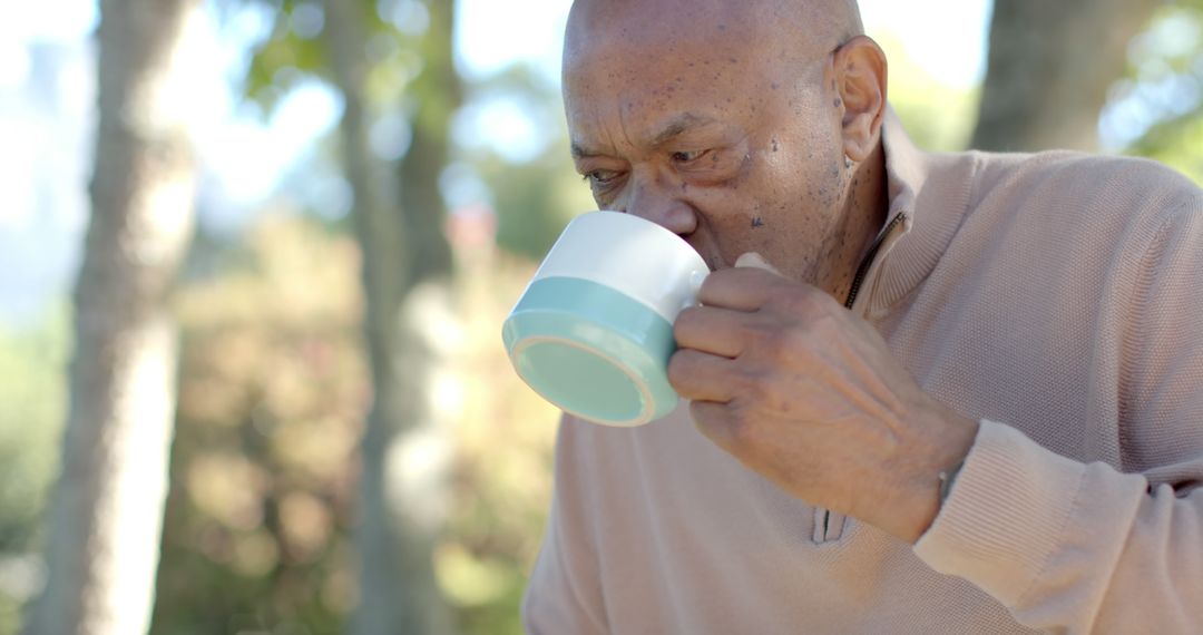 Elderly Man Enjoying Hot Drink Outdoors in Sunny Park - Free Images, Stock Photos and Pictures on Pikwizard.com