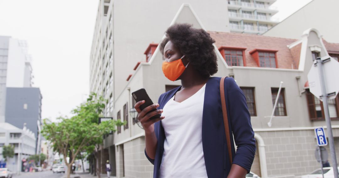 Businesswoman Wearing Orange Face Mask Using Smartphone in Urban Area - Free Images, Stock Photos and Pictures on Pikwizard.com