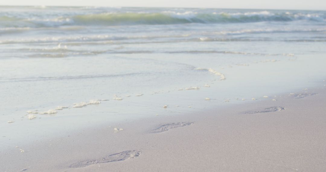 Tranquil Beach Scene with Gentle Waves and Footprints in Sand - Free Images, Stock Photos and Pictures on Pikwizard.com