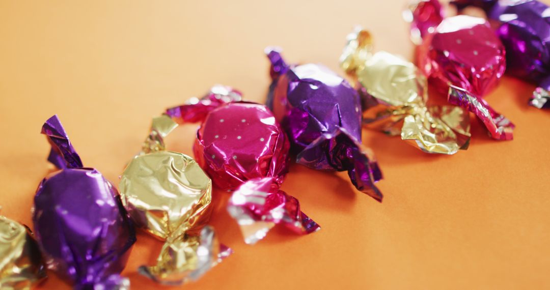 Close-Up of Assorted Wrapped Candies on Orange Background - Free Images, Stock Photos and Pictures on Pikwizard.com