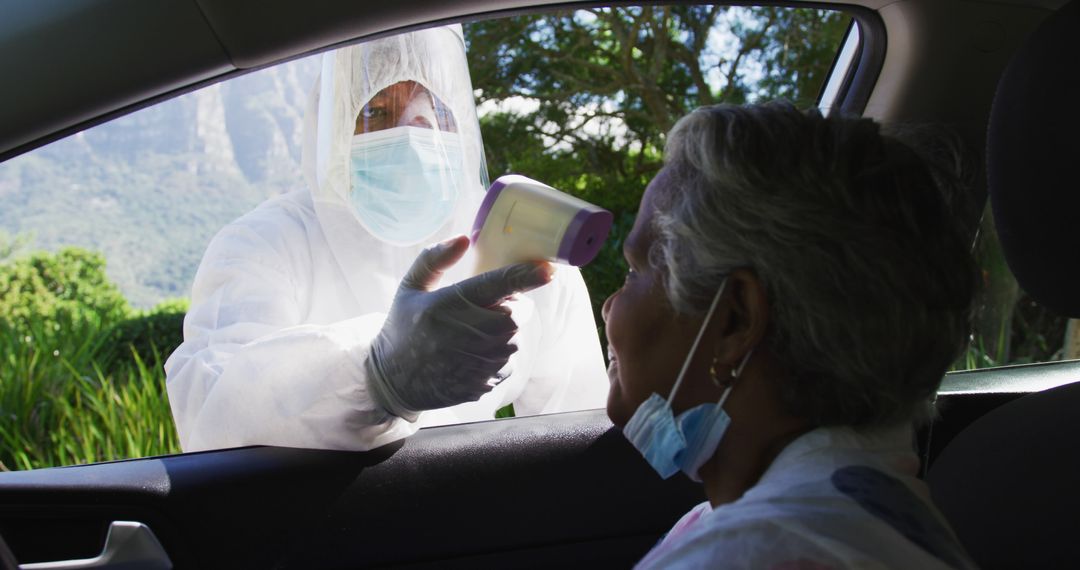 Healthcare worker measuring senior woman's temperature through car window - Free Images, Stock Photos and Pictures on Pikwizard.com