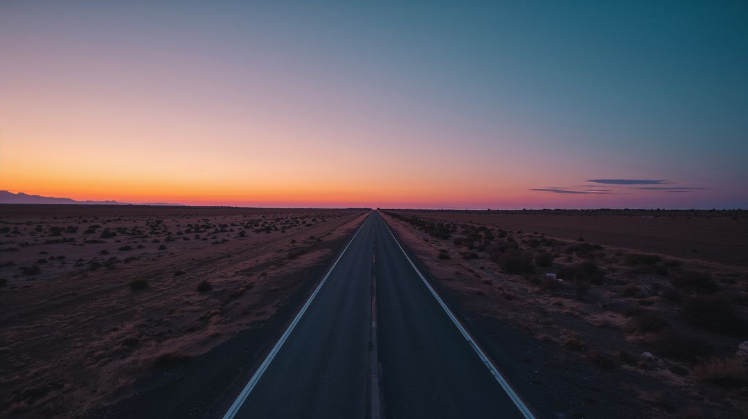 Endless Desert Highway Leading to Distant Horizon at Sunset with Colorful Twilight Sky