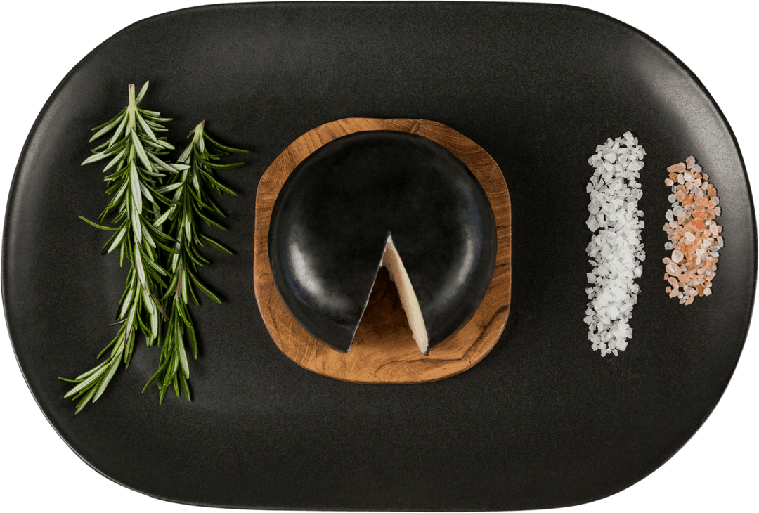 Black Cheese Wheel with Rosemary and Salt on Transparent Black Tray