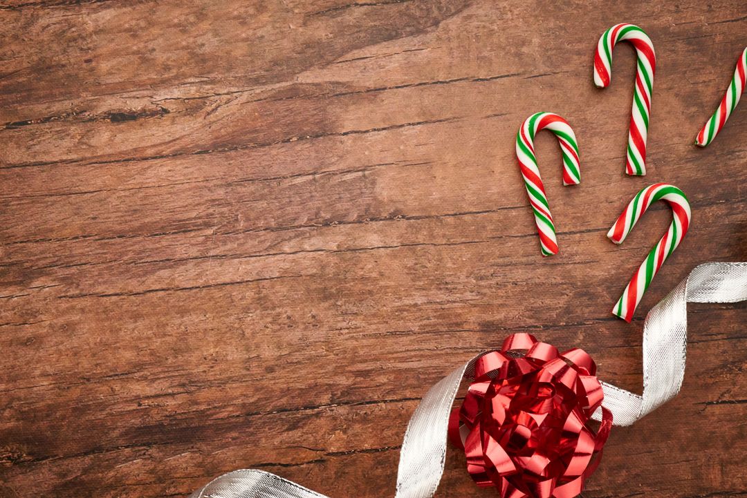 Colorful candy canes with red ribbon bows photo on wooden surface